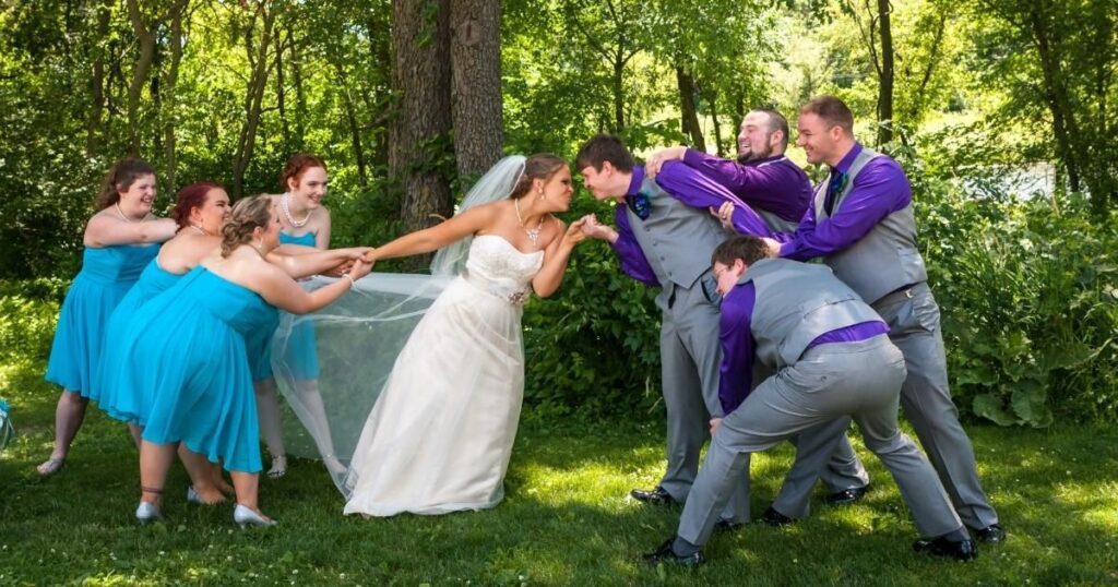 Bridal party having fun trying to pull bride and groom