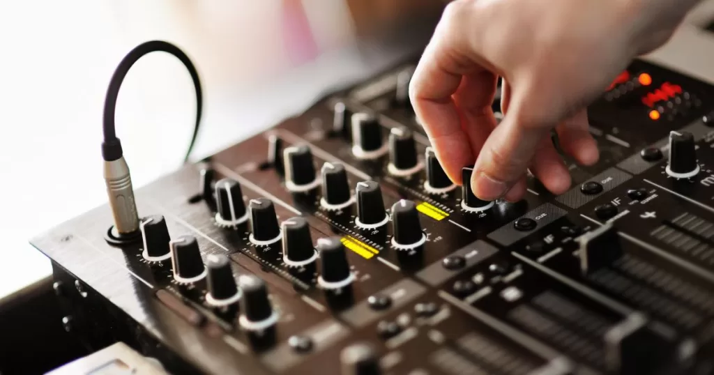 DJ adjusting the volume on a mixer